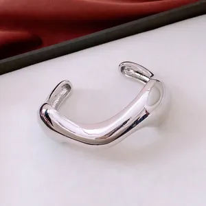 Irregular silver open bangle with polished mirror finish and minimalist organic design