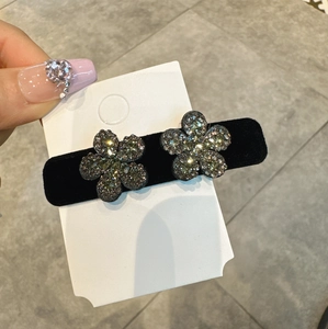 Macro di orecchini a fiore con strass grigi su base di fermaglio per capelli in velluto nero