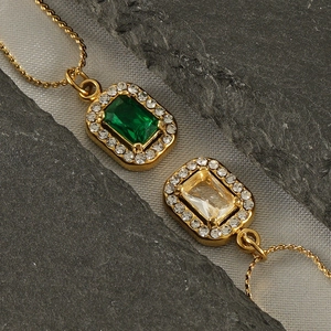 Macro view of gold 18K plated necklaces with square green and yellow zircon pendants