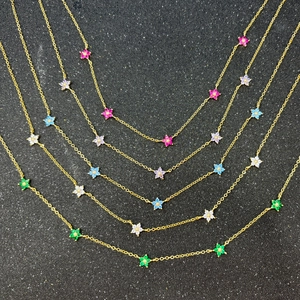 Close-up of stacked gold necklaces with colorful gemstone flower pendants in vivid tones