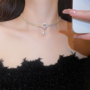 Close-up of gold-plated necklace with zircon stones and white pearl drop on model