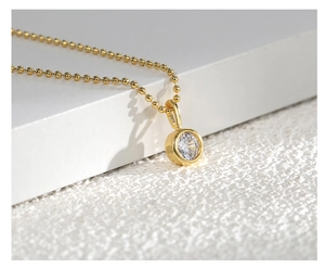Macro detail of an S925 silver gold-plated necklace featuring a round zircon pendant