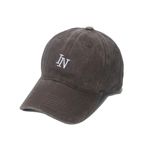 Detailed macro view of white IN embroidery on vintage washed cotton baseball cap