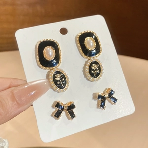 Gros plan de boucles d'oreilles perles vintage et puces nœud noir sur carte à bijoux