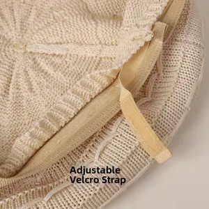 Detail of adjustable beige knitted beret showing the velcro strap for head circumference size