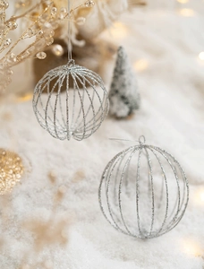 Silver hollow wire Christmas ball ornament with glitter finish on snowy background