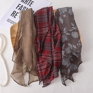Detailed flat lay of soft silk scarves with polka dots and floral patterns on wood