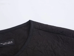 Close-up of black quilted jacket neckline and size label showing S size made in Morocco