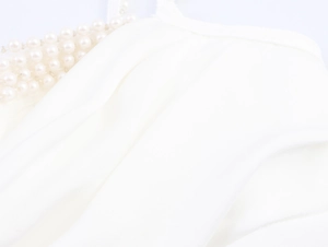 Detail of white satin dress featuring elegant pearl beadwork and soft pleated texture