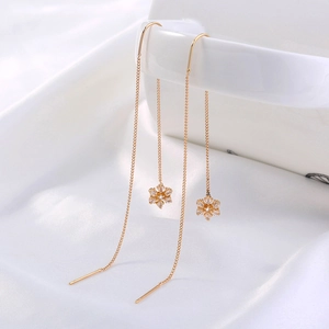 Close-up of golden snowflake ear threaders with zircon crystals on white silk