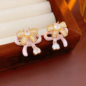 Detail of pink bow earrings with rhinestones on a brown velvet jewelry box edge