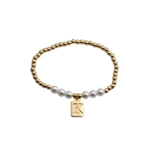 Close-up of gold bead bracelet with five white pearls and a rectangular K letter pendant