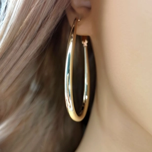 Minimalist gold-polished large hoop earrings shown on a model for a classic retro style