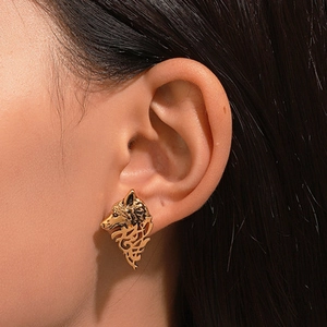 Close-up of golden wolf head earring with Celtic knot cutout design on model ear