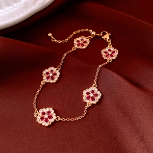 Detail of 18k rose gold flower bracelet with red stones on dark red silk background