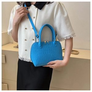 Close-up of blue crocodile texture shell bag with gold hardware and adjustable strap