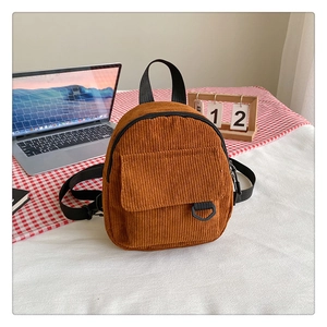 Détail d'un sac à dos en velours côtelé caramel avec poche avant sur nappe à carreaux