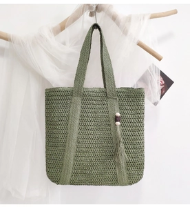 Detail of green straw tote bag with wood bead tassel hanging on wooden rod with soft veil