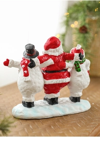 Rear view of resin Santa and snowmen figurines on wood with warm holiday lights