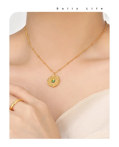 Detail of gold sunburst coin necklace with colorful center stone on model neck
