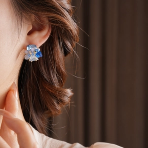 Close-up of elegant flower cluster earring with blue crystals on model's ear