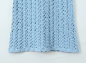 Détail macro du tricot bleu clair avec motifs de vagues évidés et finition de bord côtelé