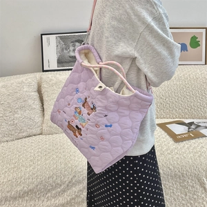 Detail of purple quilted shoulder bag featuring colorful cartoon dog embroidery and pink straps