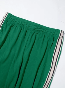 Detail of green sports joggers featuring elastic waistband and side stripe webbing