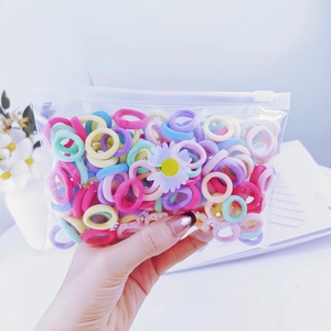 Colorful cotton hair ties for babies in a daisy print zipper bag held by hand