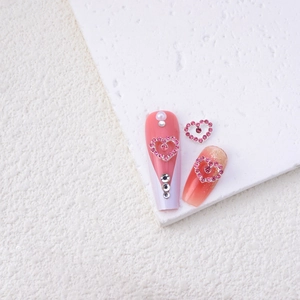 Detailed macro view of heart-shaped alloy nail charms with pink rhinestones and pearls