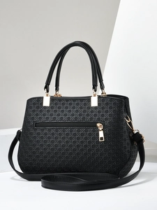 Close-up of black leather handbag featuring intricate woven texture and gold zippers