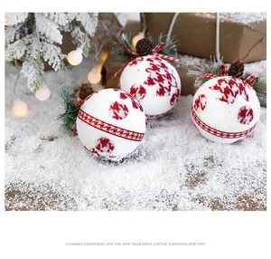 Close-up of three festive foam Christmas balls with pine cones and needles on faux snow