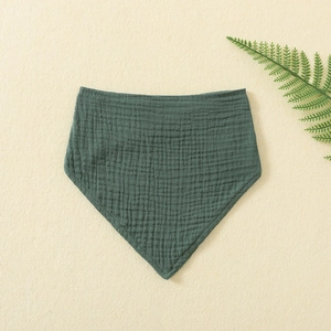 Detail of dark green muslin cotton baby bib with soft wrinkled texture and edge binding