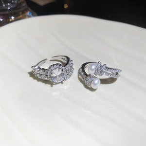 Macro shot of silver zircon rings with oval crystal and pearls on a white porcelain plate