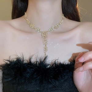 Gros plan d'un collier doré élégant en forme de feuille avec pampille et cristaux brillants