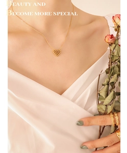 Detail shot of heart-shaped grid necklace and matching gold rings on elegant model