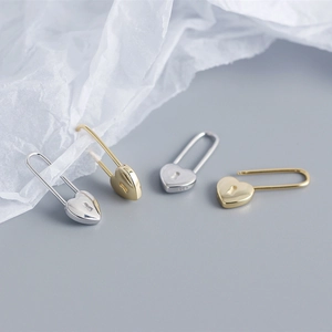 Detailed view of gold and silver S925 sterling silver heart lock earrings on white tissue paper