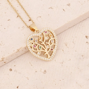 Detailed close-up of golden heart pendant with tree of life and colorful zircon inlay