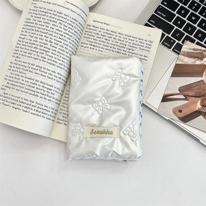 Close-up of white quilted bow passport cover with Sezakka label on a minimal desk set