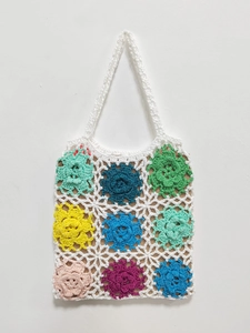 Close-up of handmade crochet tote bag featuring colorful woven flower patterns and texture
