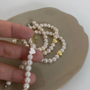 Close-up of a natural freshwater pearl necklace with a delicate heart pendant charm