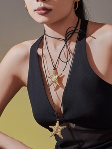Détail du collier pendentif étoile de mer dorée avec texture sur cordon noir