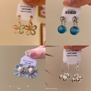 Detail of four unique silver earrings including floral, blue bead, and pearl styles