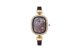 Detail of rose gold oval watch with marble dial and rhinestone bezel on brown leather strap