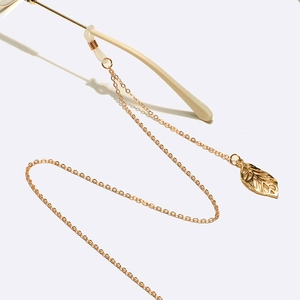 Detailed view of golden metal eyewear chain with hollow leaf pendant and silicone loops