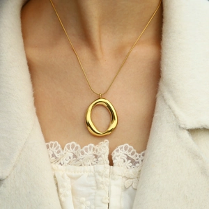 Dettaglio di una collana con ciondolo circolare vuoto placcata in oro 18K su modella