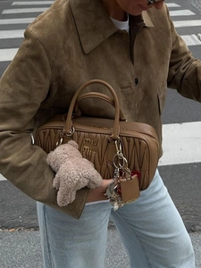 Street style view of a brown quilted leather handbag with gold logo and charms