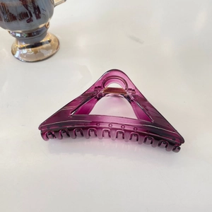 Macro shot of translucent purple triangular hair claw clip with metallic spring detail