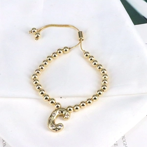 Detail of golden bead bracelet featuring a sparkling rhinestone-encrusted letter C charm