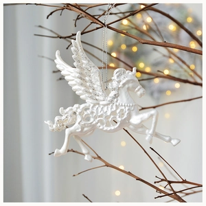 Detailed view of white resin Christmas pegasus ornament with silver glitter on tree branch